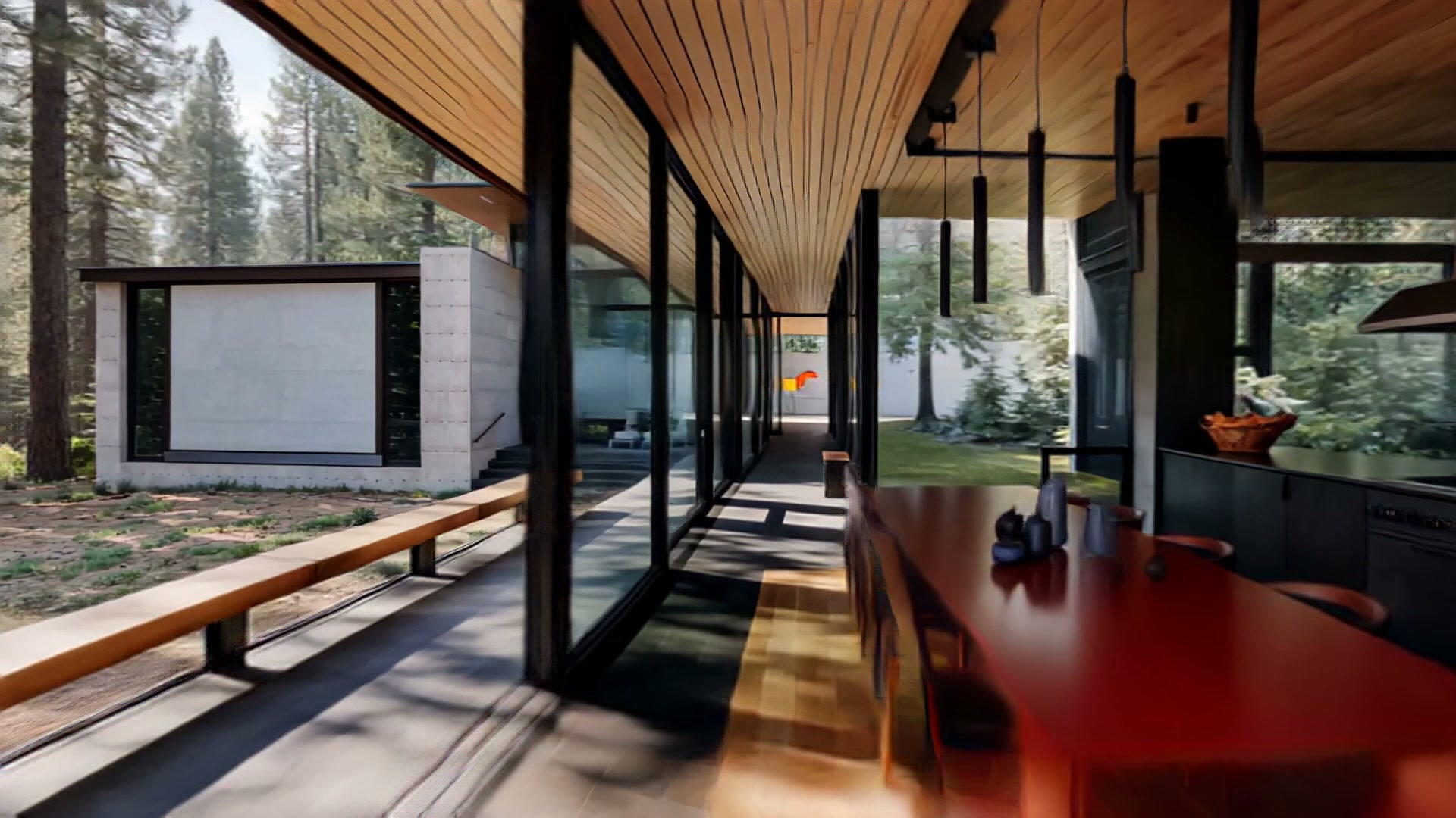 Long open dining hall with red table and forest beyond
