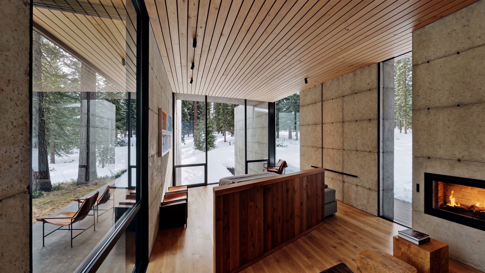 Long living room with fireplace and snowy forest beyond